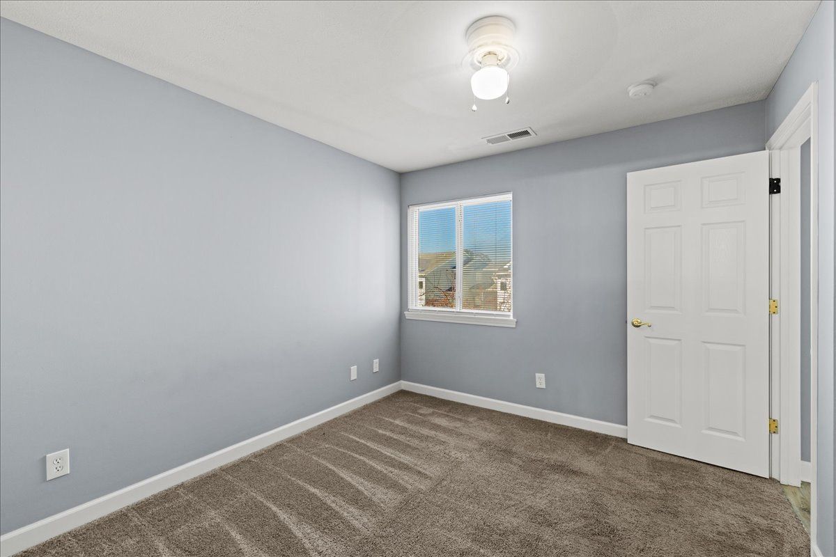 An empty bedroom with a window and a ceiling fan.