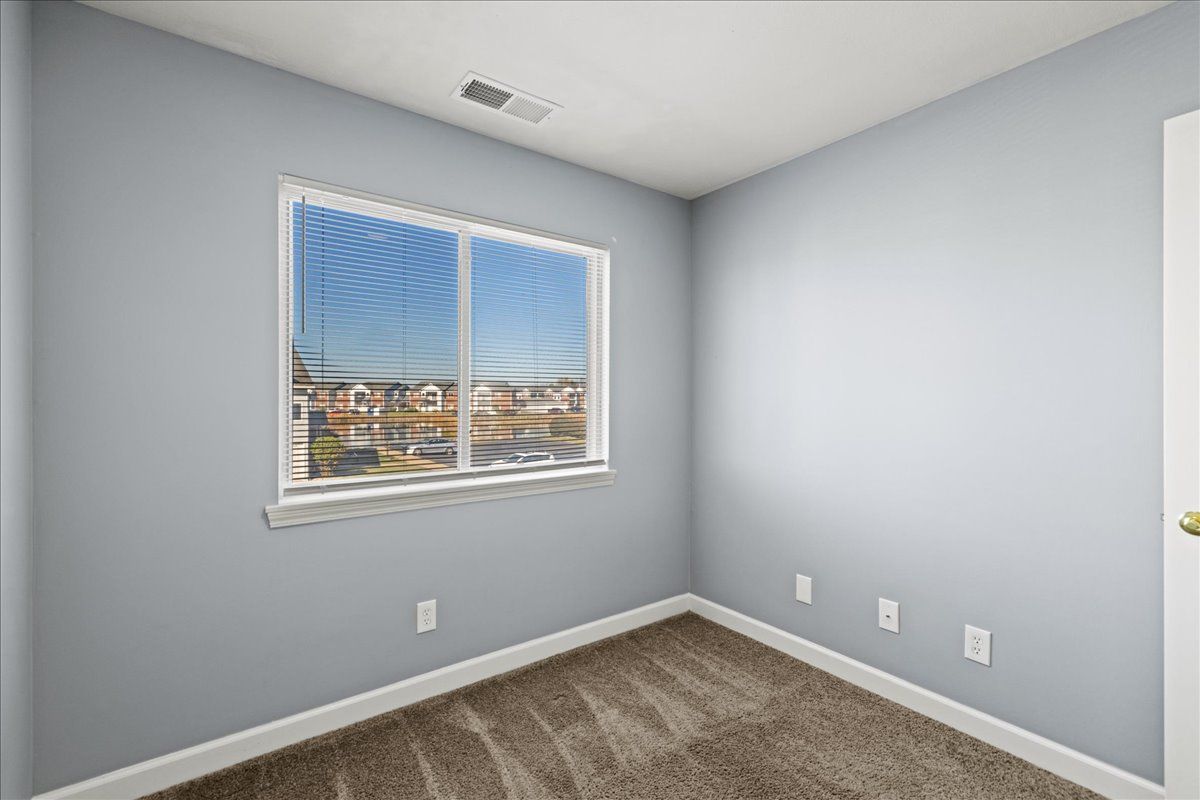 An empty bedroom with a window and carpet.