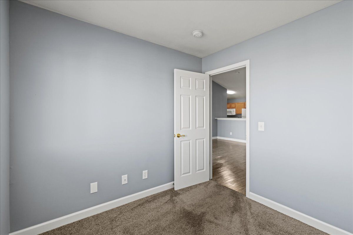 An empty room with a door open and a carpeted floor.