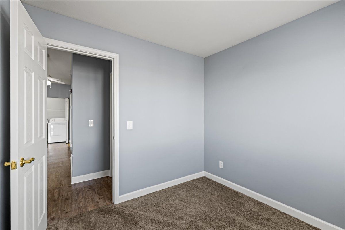 An empty bedroom with a door open and a carpeted floor.