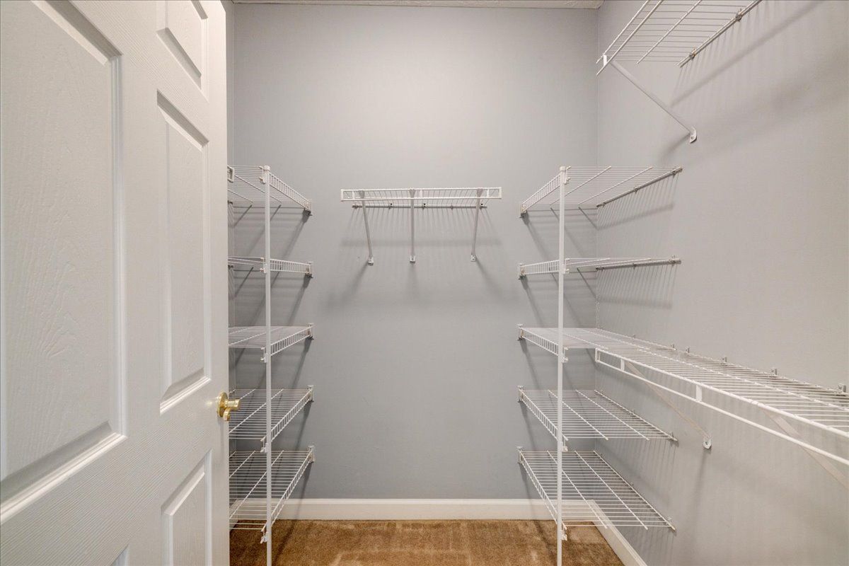 A walk in closet with lots of shelves and a door.