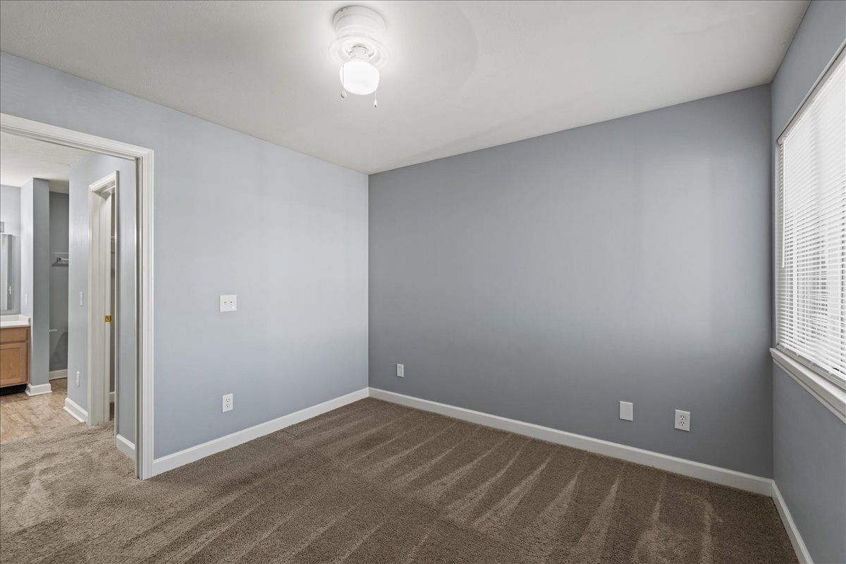 An empty bedroom with gray walls and a brown carpet.