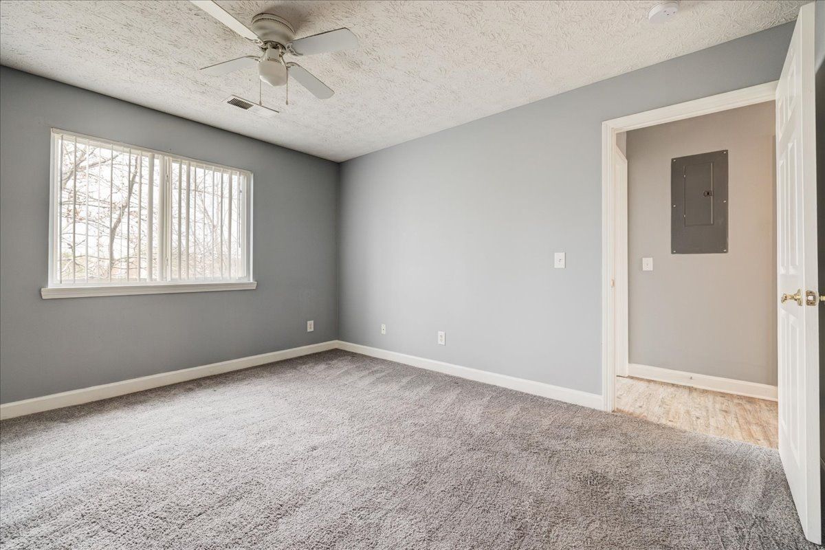 An empty bedroom with a ceiling fan and a window.