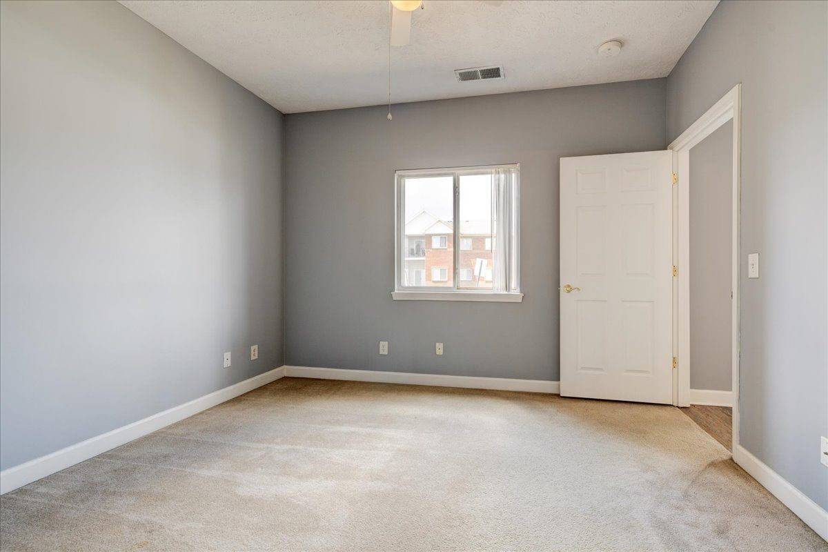 An empty bedroom with a ceiling fan and a window.