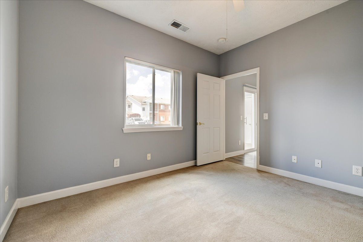 An empty bedroom with gray walls and a carpeted floor.