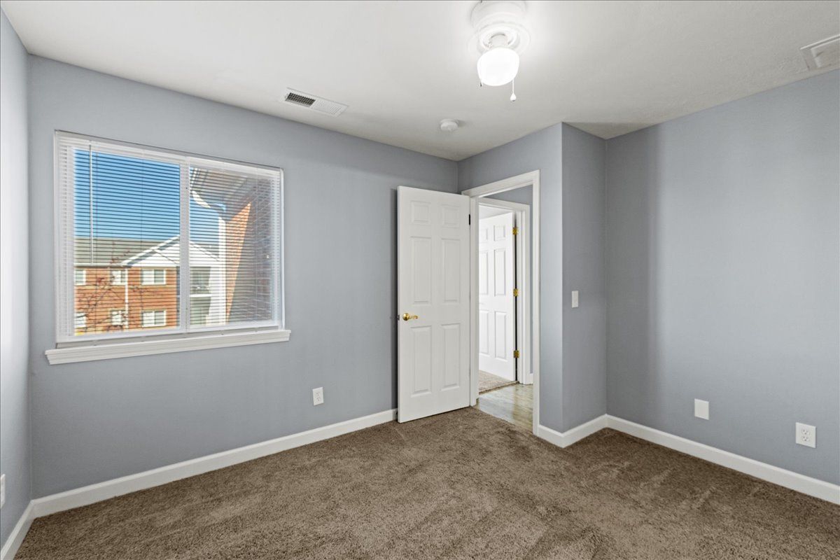 An empty bedroom with a window and a ceiling fan.