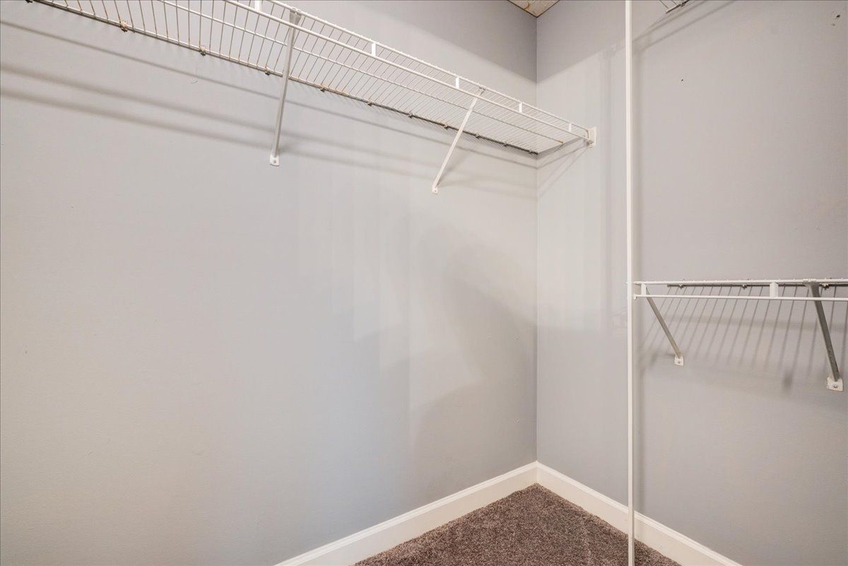 An empty walk in closet with a wire rack and a carpeted floor.