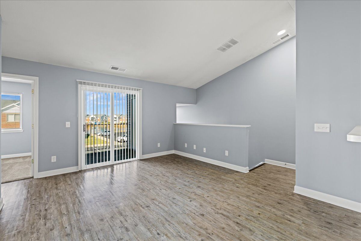 An empty living room with hardwood floors and sliding glass doors.