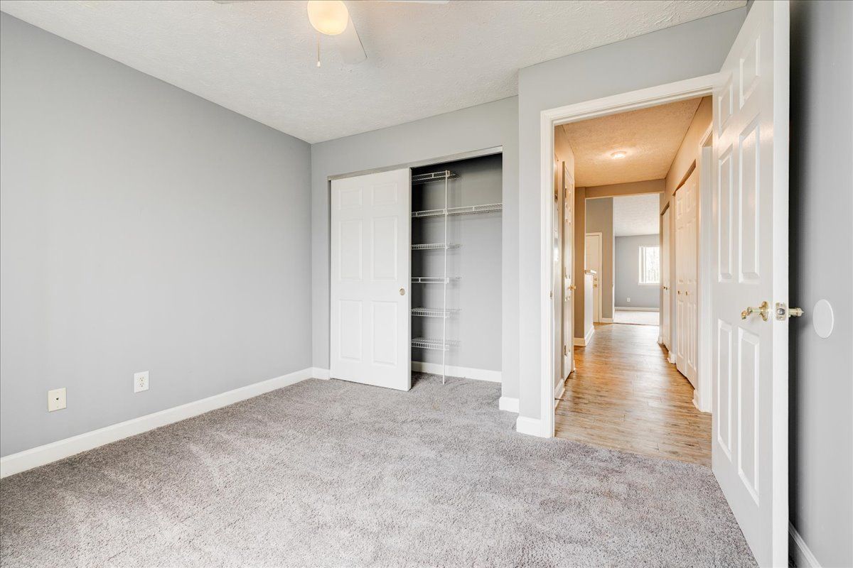An empty bedroom with a ceiling fan and a closet.