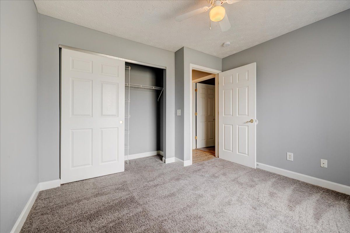 An empty bedroom with a ceiling fan and a closet.