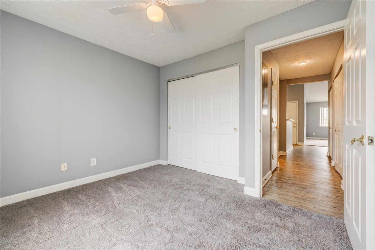 An empty bedroom with a ceiling fan and a closet.