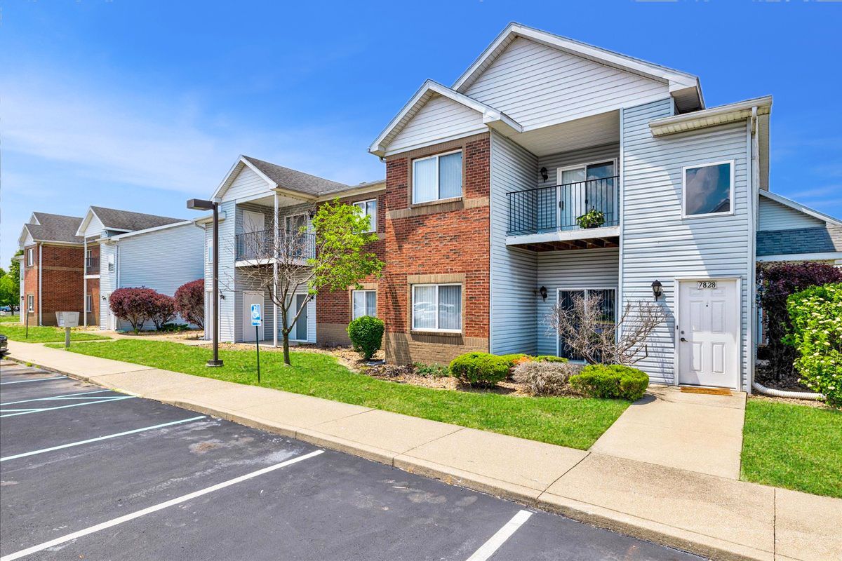A row of apartment buildings with a parking lot in front of them.