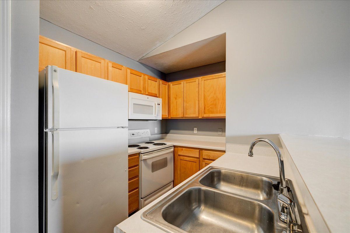 A kitchen with a sink , refrigerator , stove and microwave.