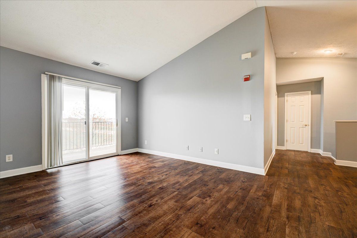 An empty living room with hardwood floors and sliding glass doors.