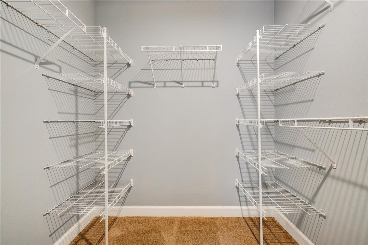 A walk in closet with lots of shelves and a gray wall.