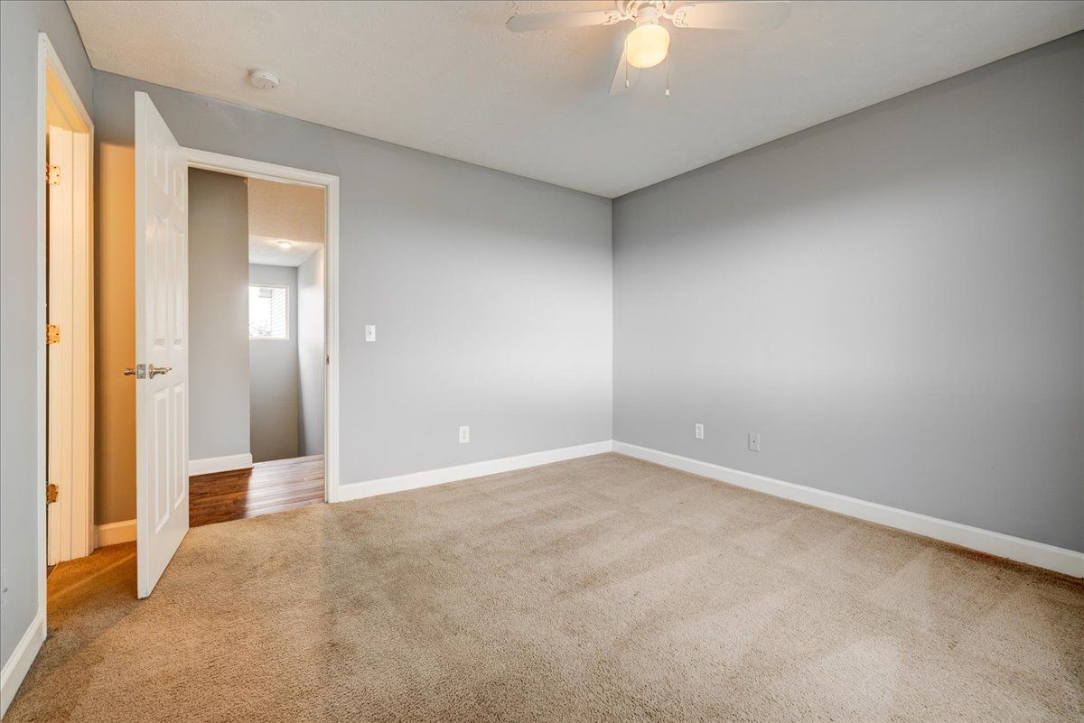 An empty bedroom with a ceiling fan and a carpeted floor.