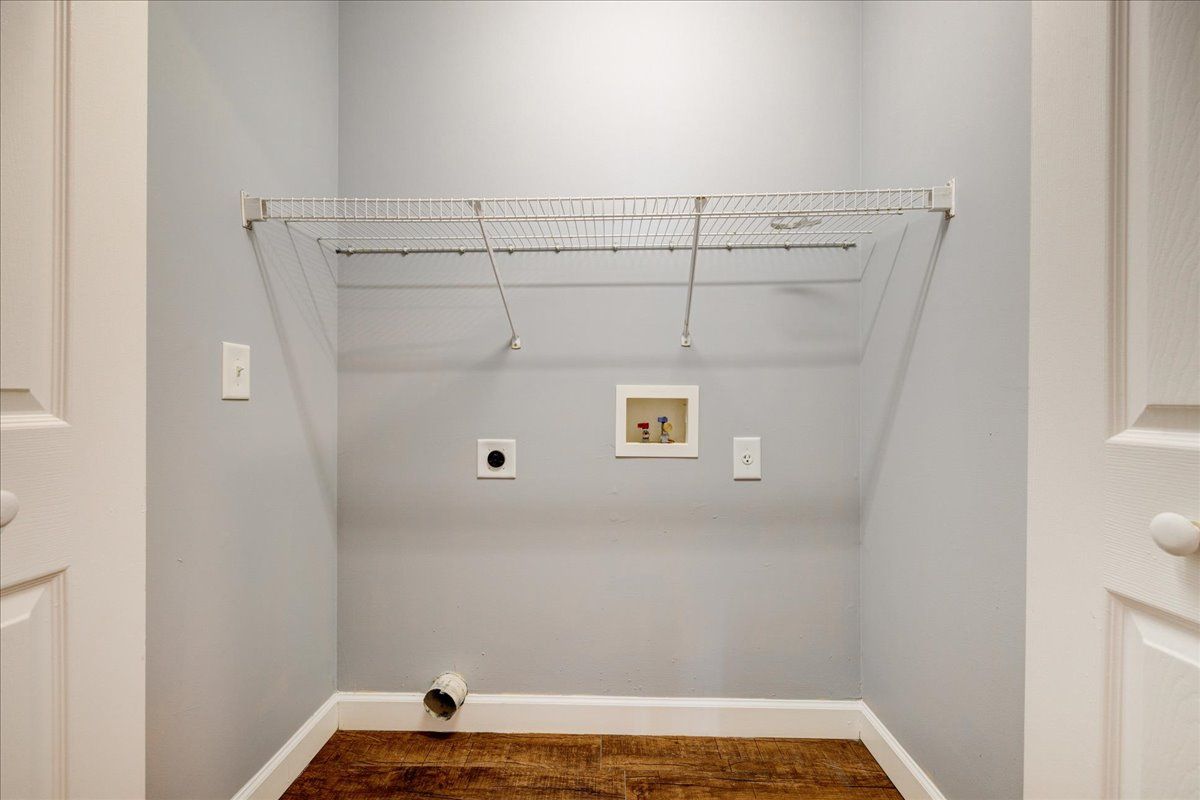 A laundry room with a wooden floor and a clothes rack.