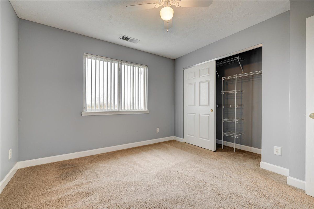 An empty bedroom with a ceiling fan and a closet.