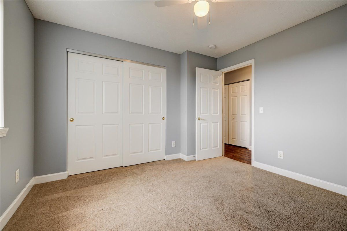 An empty bedroom with a ceiling fan and a closet.