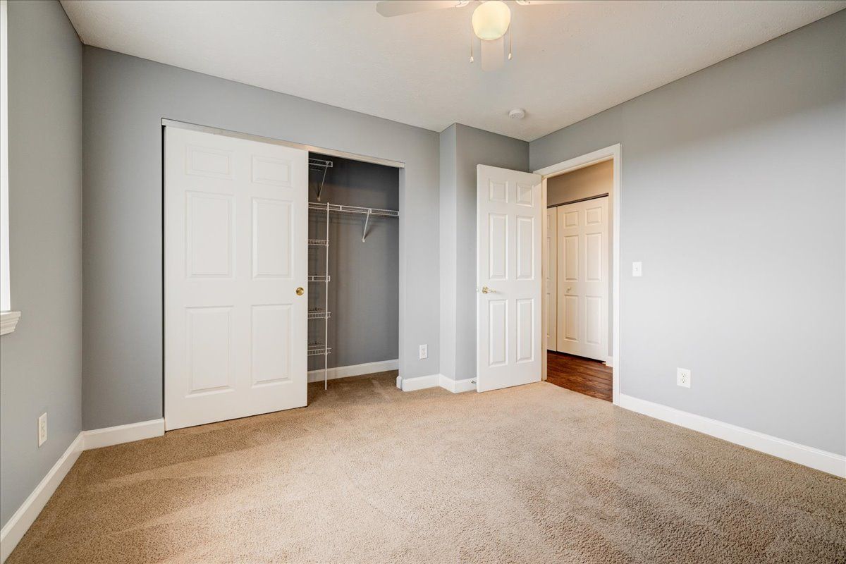 An empty bedroom with a ceiling fan and a closet.