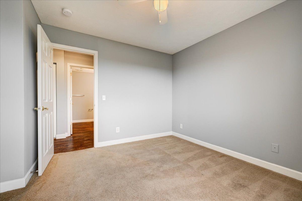 An empty bedroom with a carpeted floor and gray walls.