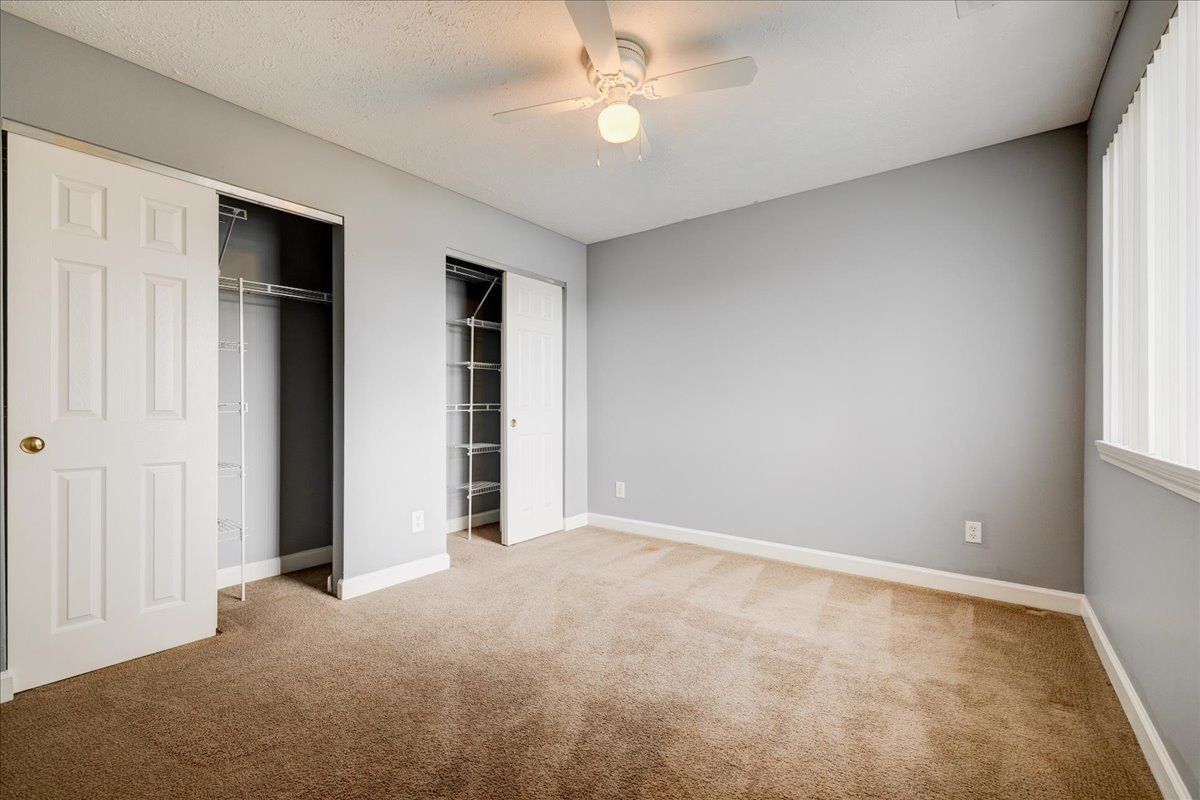 An empty bedroom with a ceiling fan and a walk in closet.