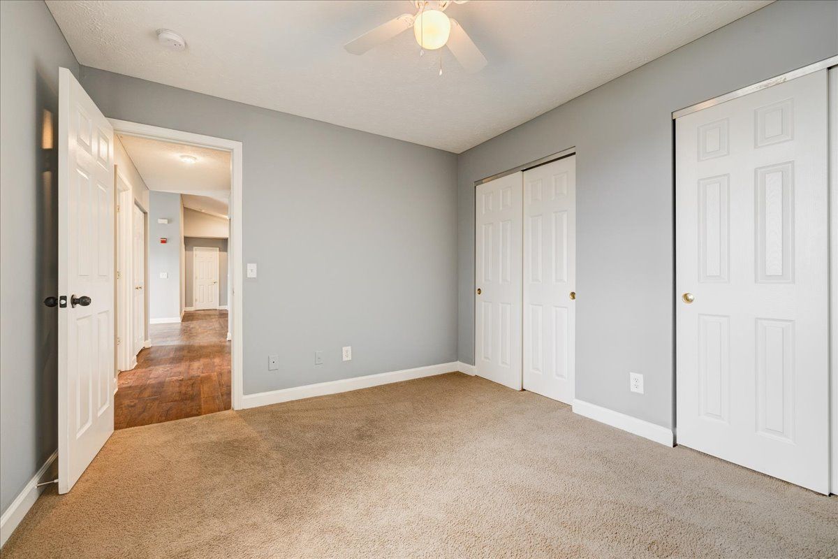 An empty bedroom with a ceiling fan and closets.