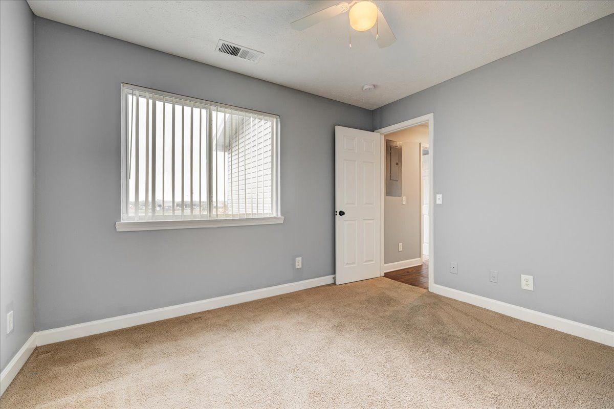 An empty bedroom with a ceiling fan and a window.