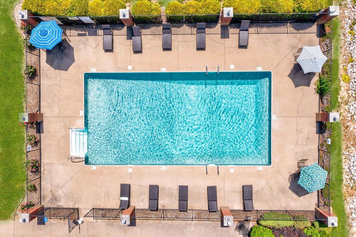 An aerial view of a large swimming pool surrounded by chairs and umbrellas.