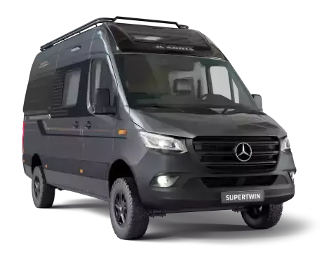Dark gray camper van with black off-road tires, a roof rack, and a Mercedes-Benz emblem.