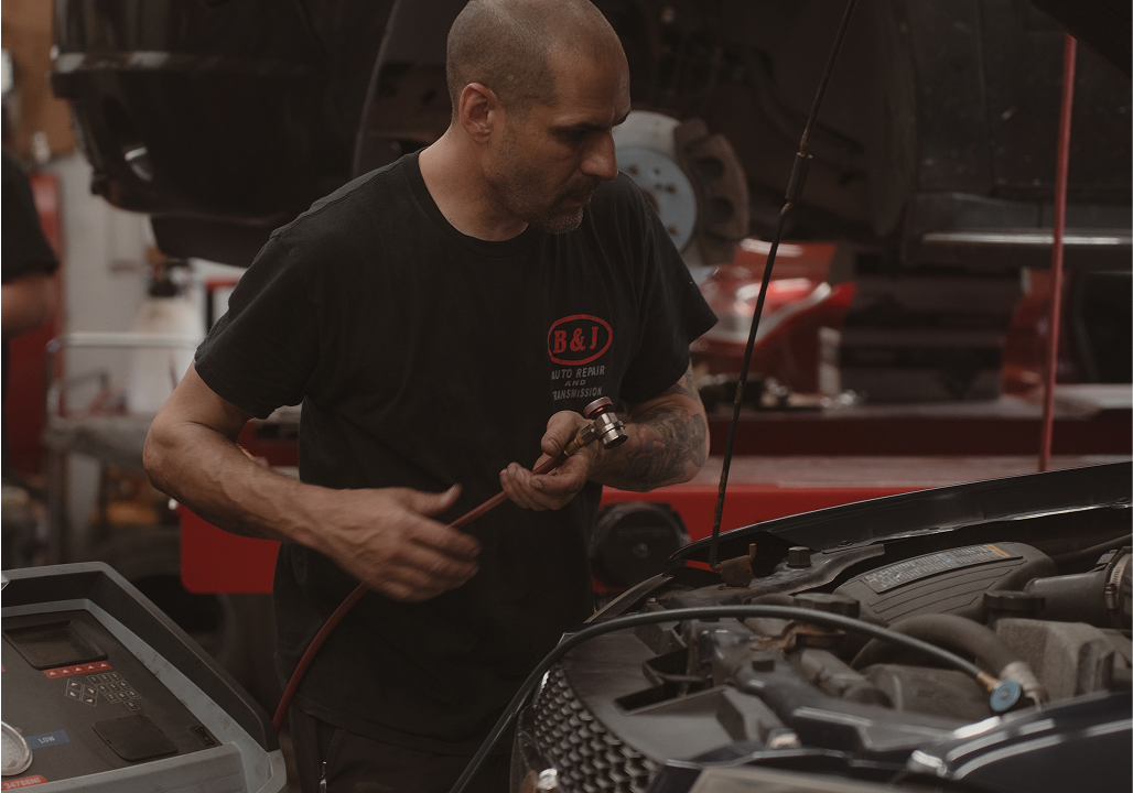 Interior of a cluttered shop with shelves, tools, and a person walking towards the back. | B&J Auto Repair & Transmission