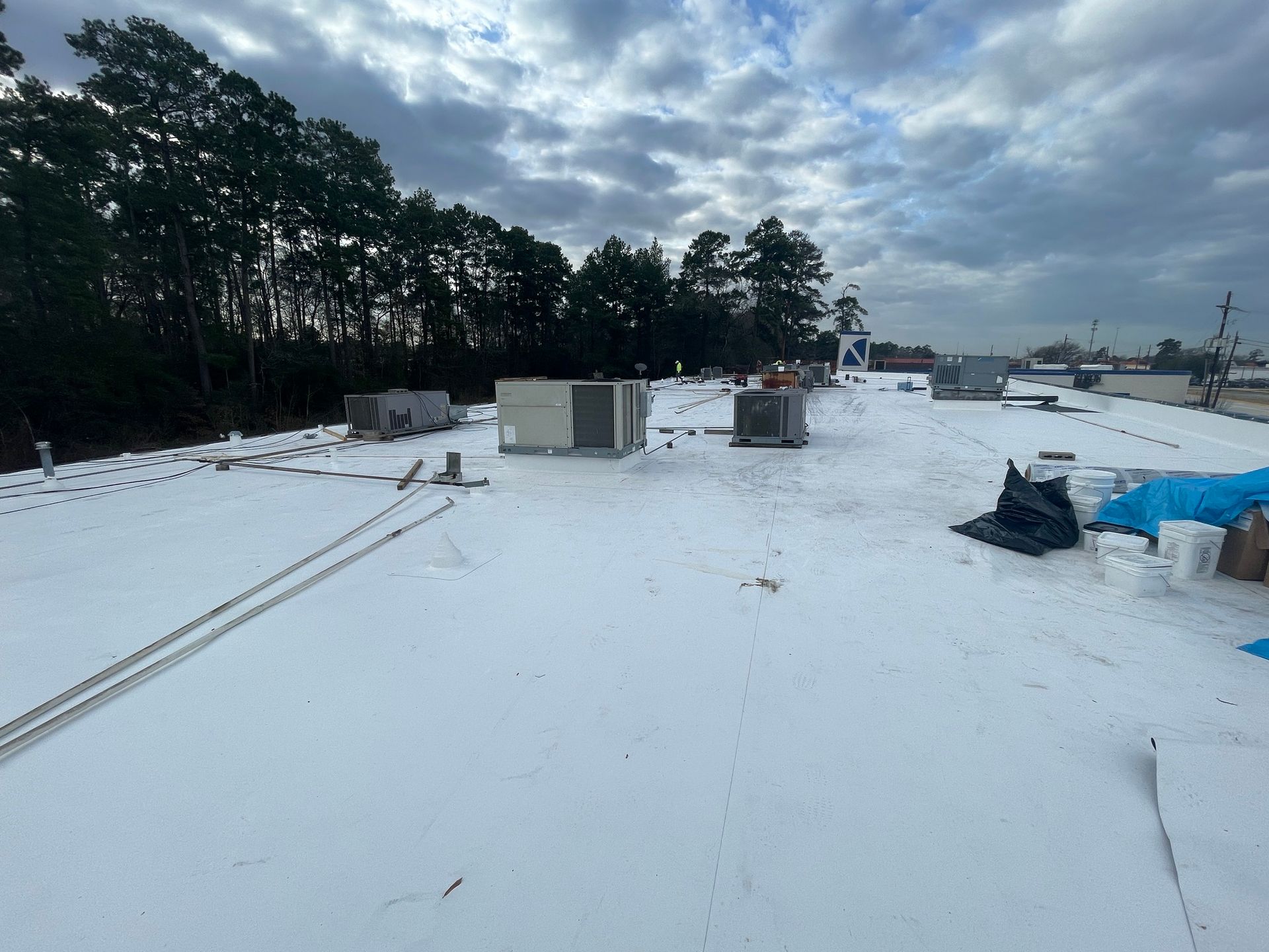 The roof of a building is covered in snow and there are trees in the background.