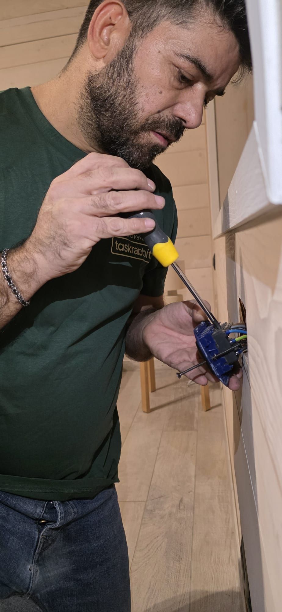 Mobile porta TV in legno e contenitore a parete con rivestimento protettivo su una parete bianca, in una stanza vuota.