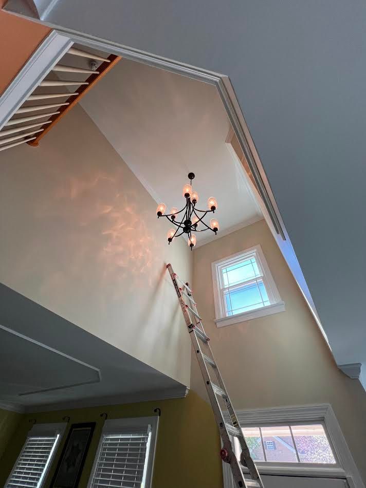 Tall living room ceiling with a modern chandelier and two windows, viewed from below