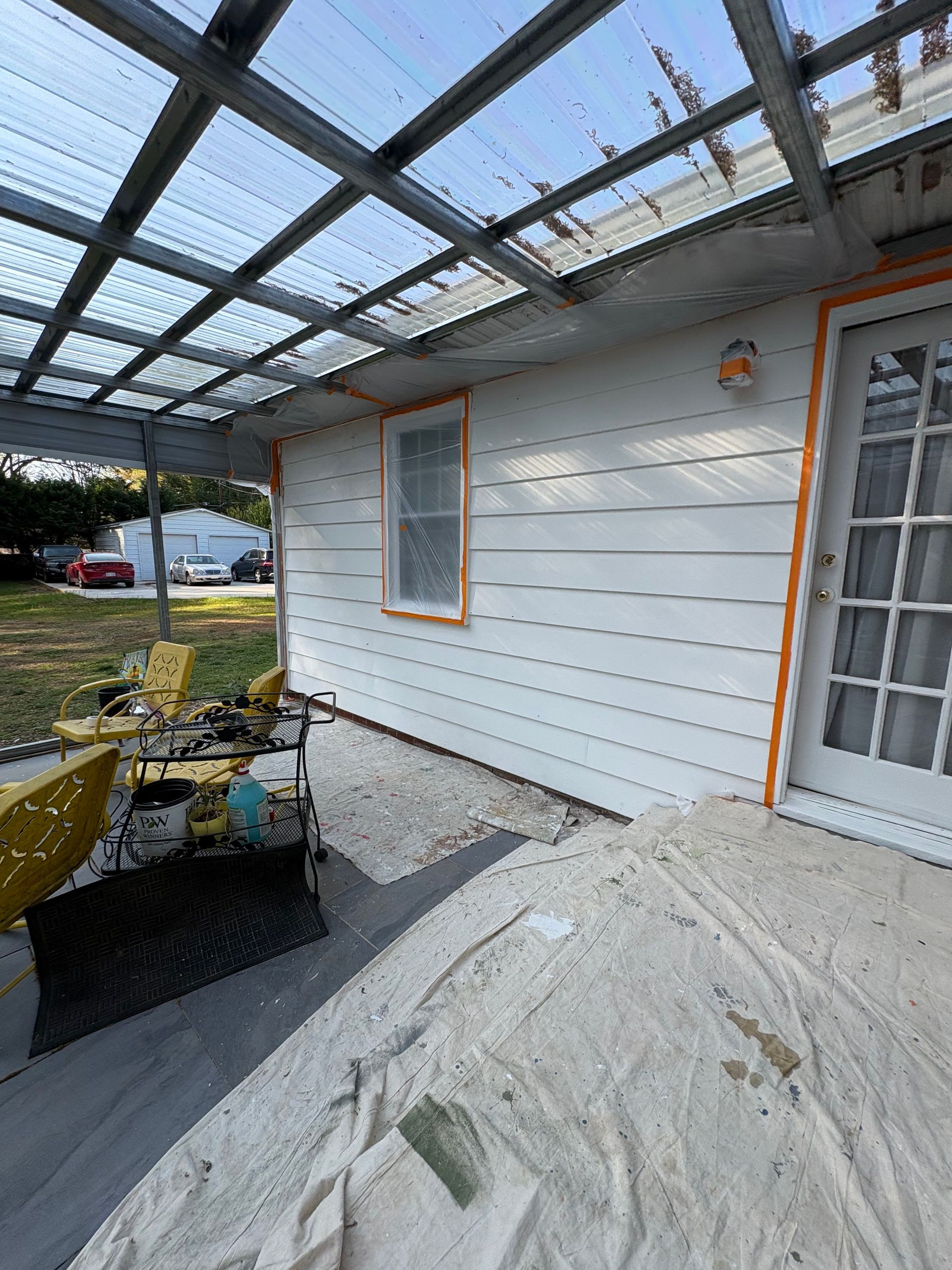 Covered porch under construction with white siding, windows, and a wire grid roof frame.