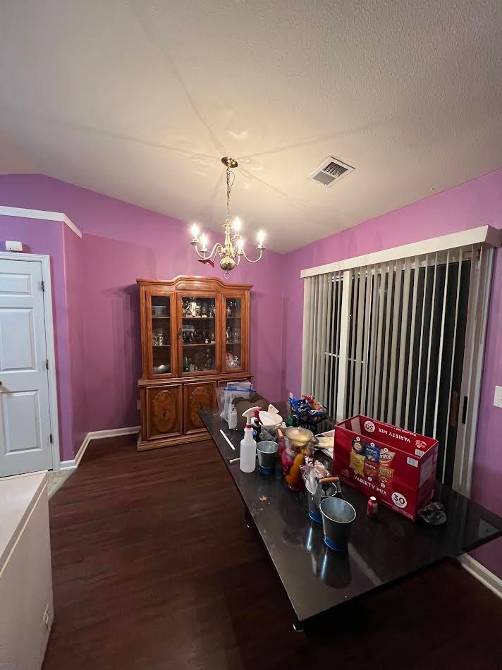 Dining room with purple walls, dark wood table set with items, china cabinet, and sliding blinds.