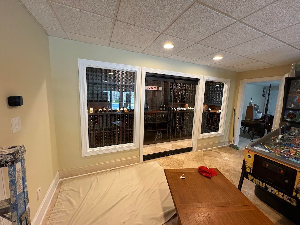 Basement room with large windows, a covered couch, coffee table, and red object on top.