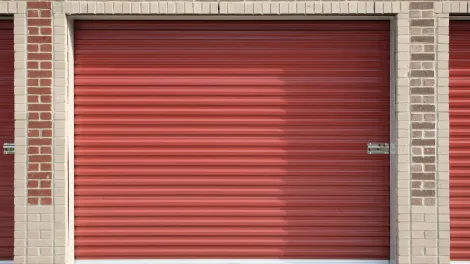 A row of red garage doors on a brick building.