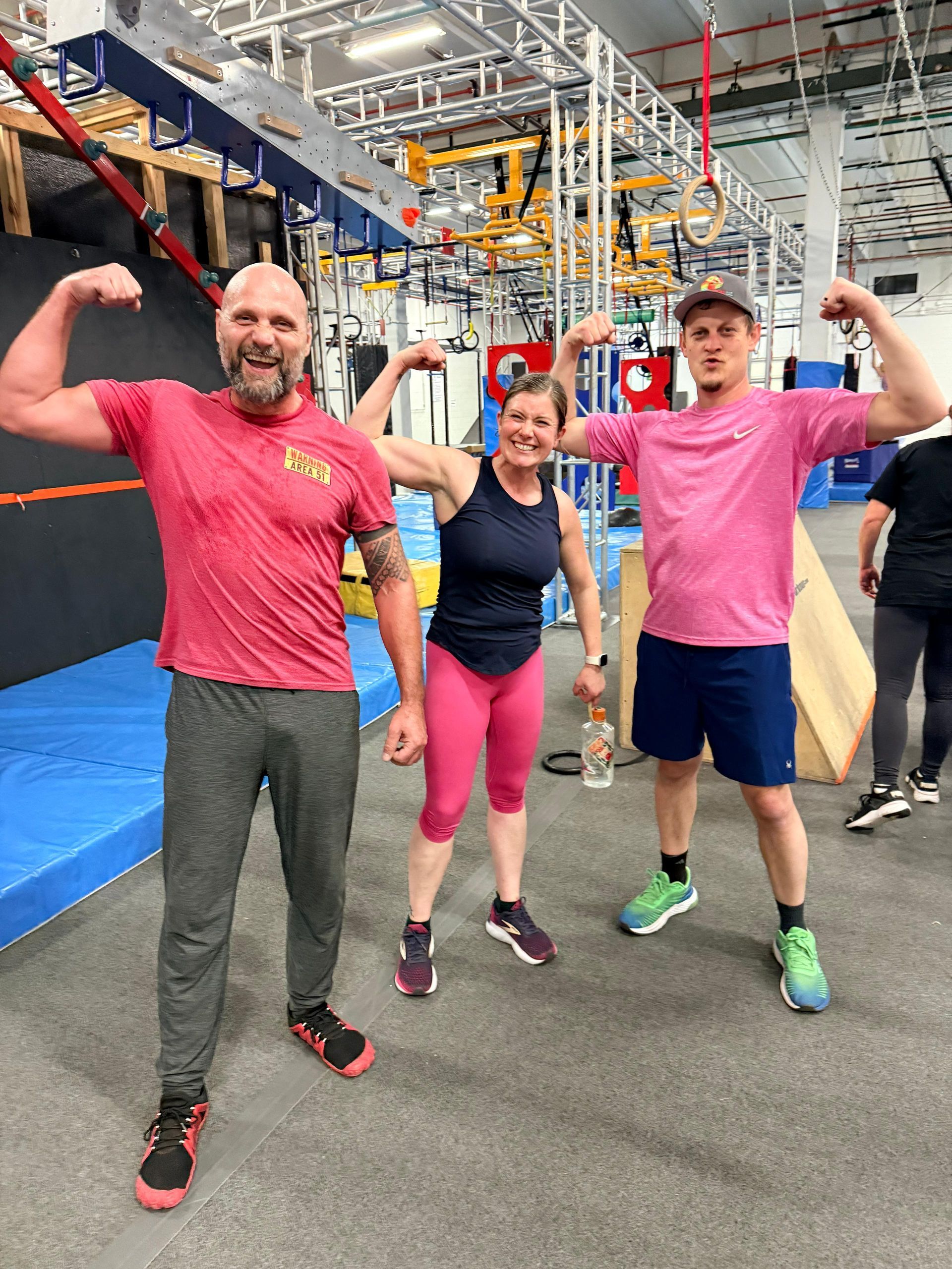 Three Obstacle Course racers flexing in the gym