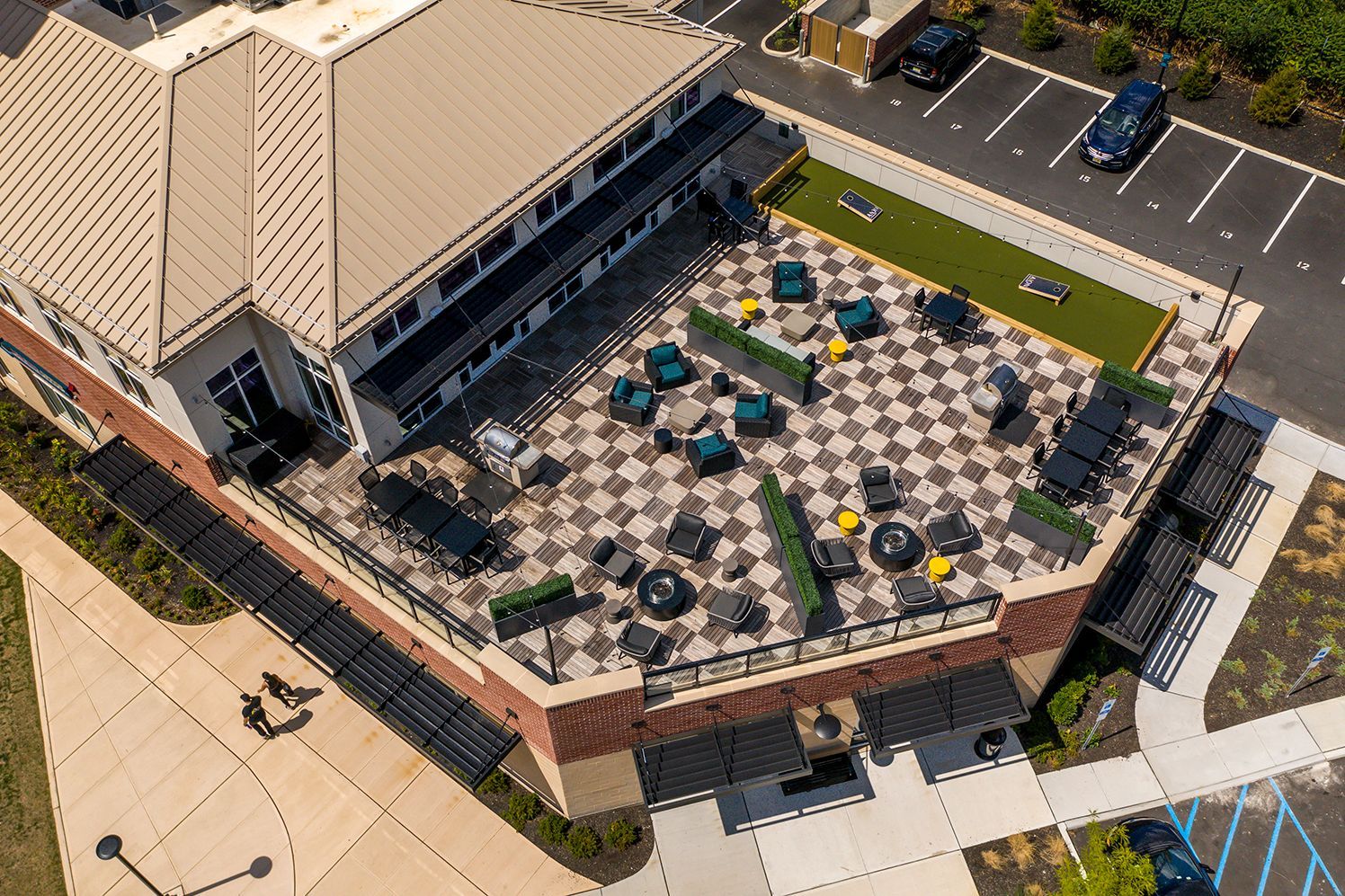 Aerial view of a building with a rooftop patio, checkered tile, seating, and a small putting green.