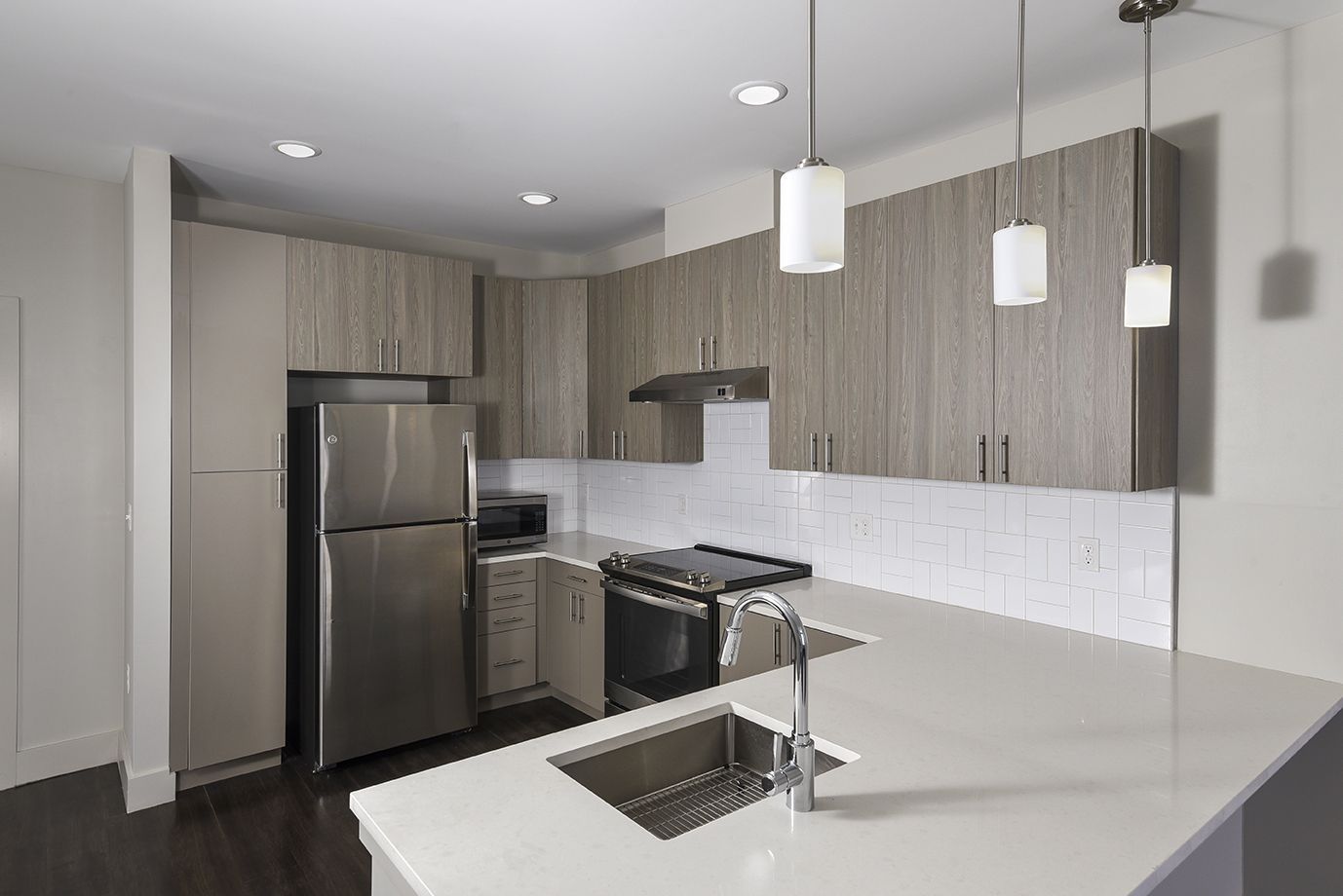 Modern kitchen with light gray cabinets, stainless steel appliances, and white countertop island.