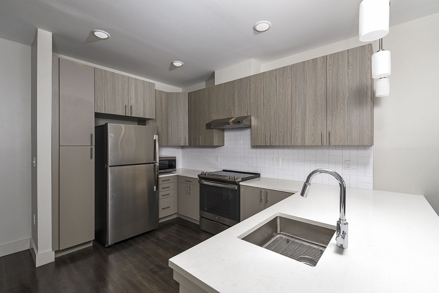 Modern kitchen with stainless steel appliances, light wood cabinets, and white countertops.