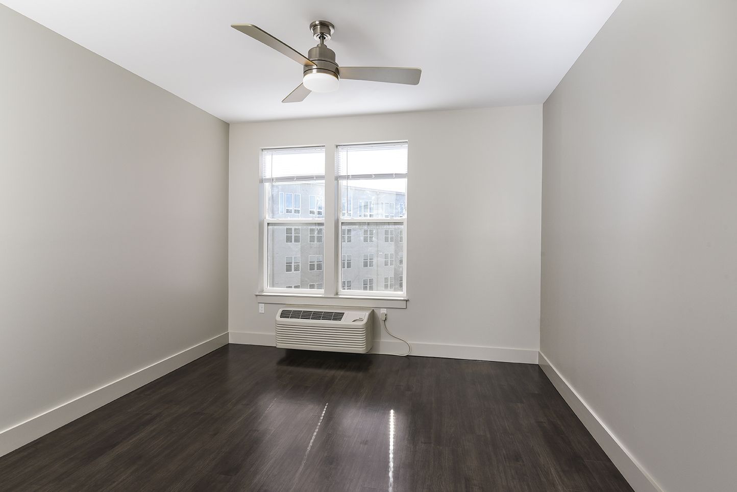 Empty room with hardwood floors, a window, and a ceiling fan.
