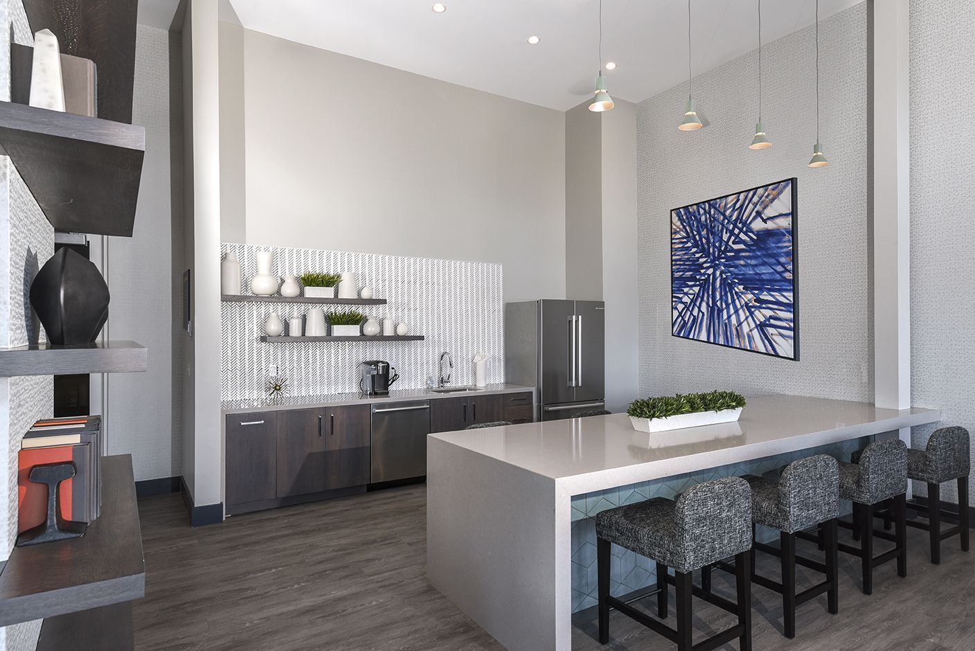 Modern kitchen with a gray island, stainless steel fridge, art, and seating.