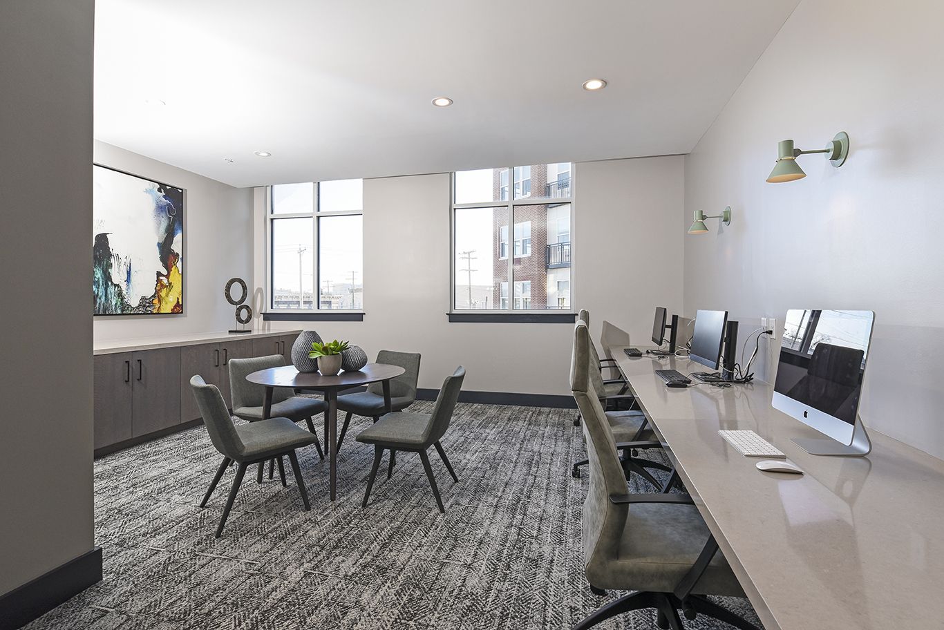 Computer lab with a round table, chairs, and several computers along a wall.