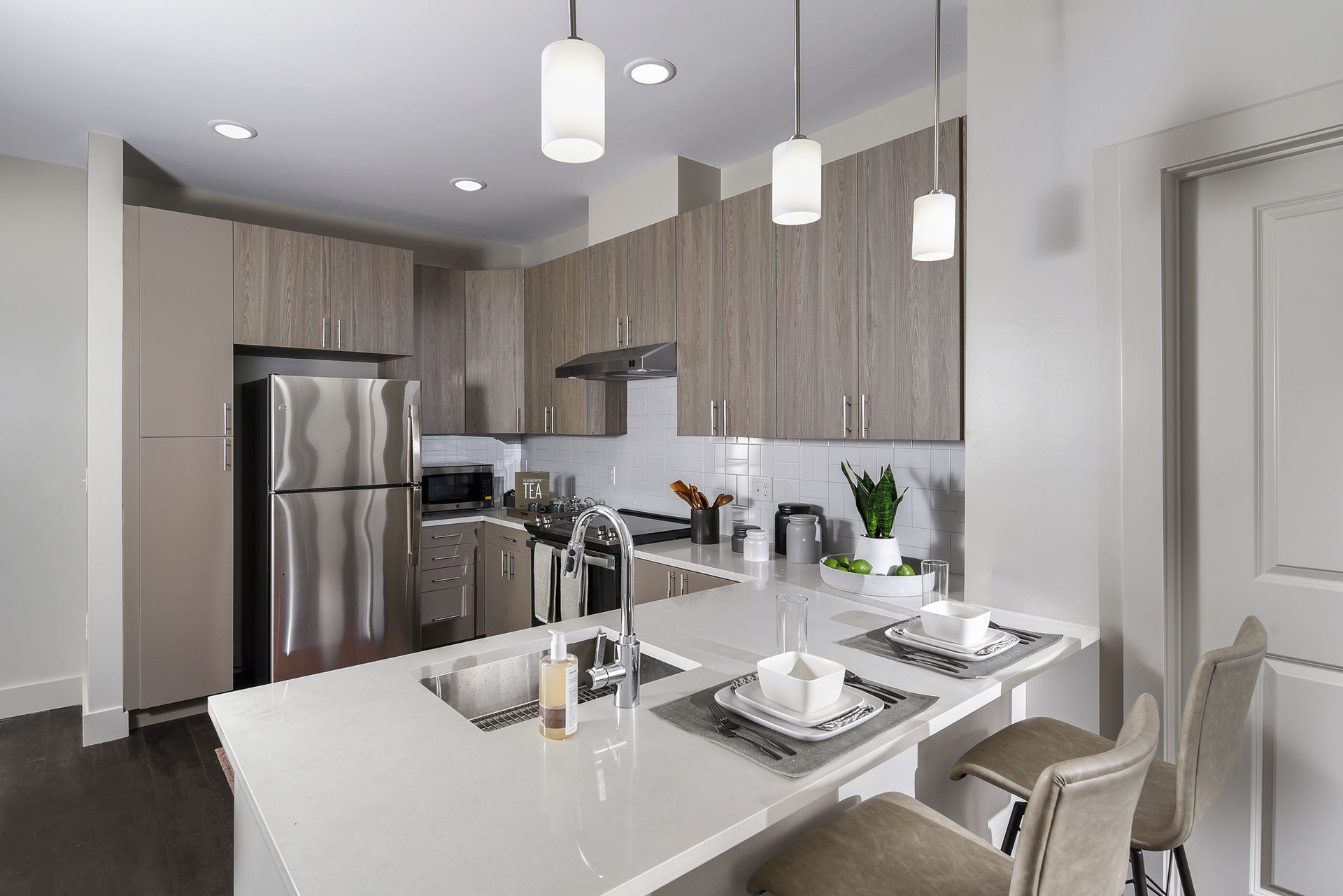 Modern kitchen with stainless steel appliances, light wood cabinets, and white countertop island with two place settings.