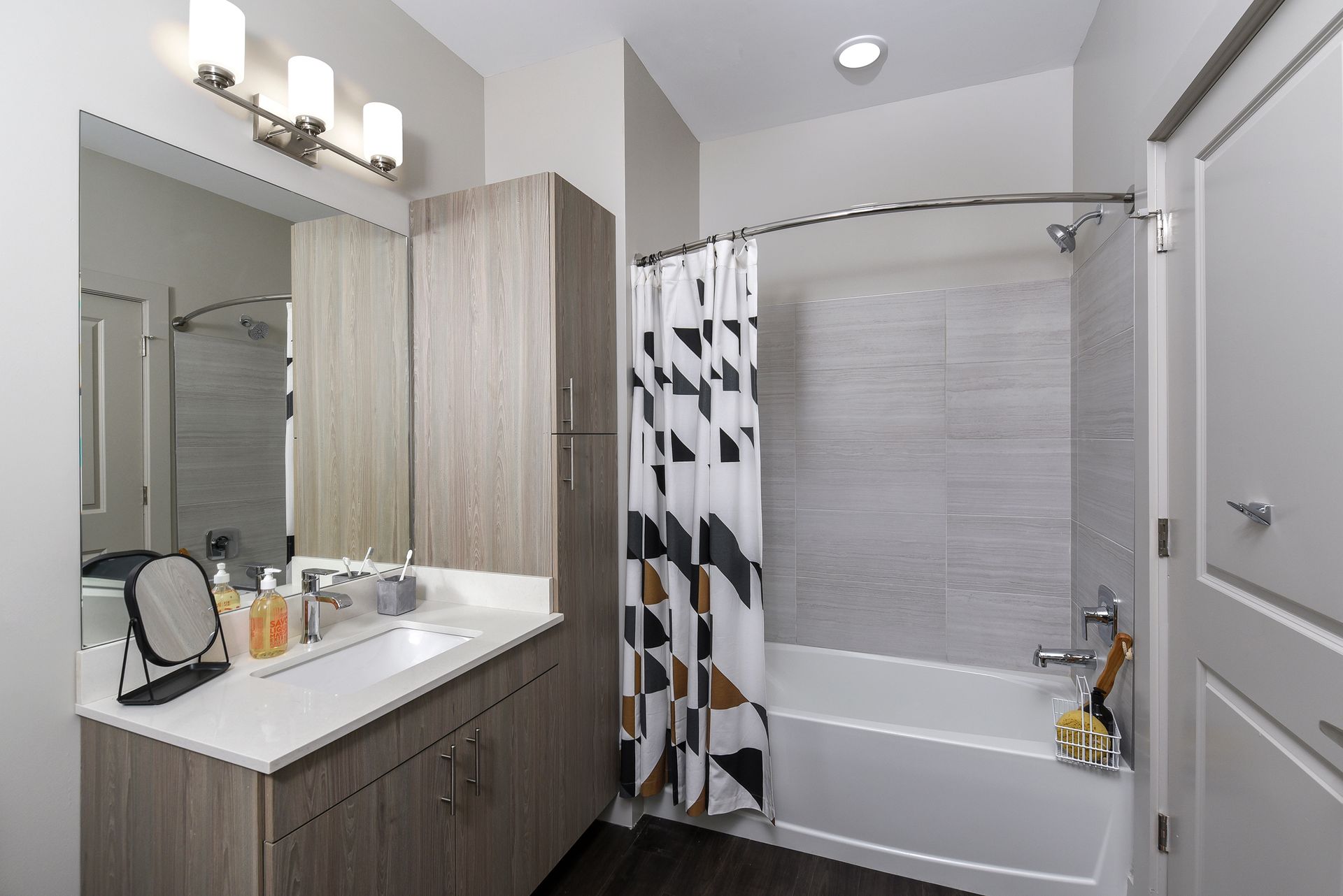 Modern bathroom with a white tub and shower curtain, grey walls, and light-colored vanity.
