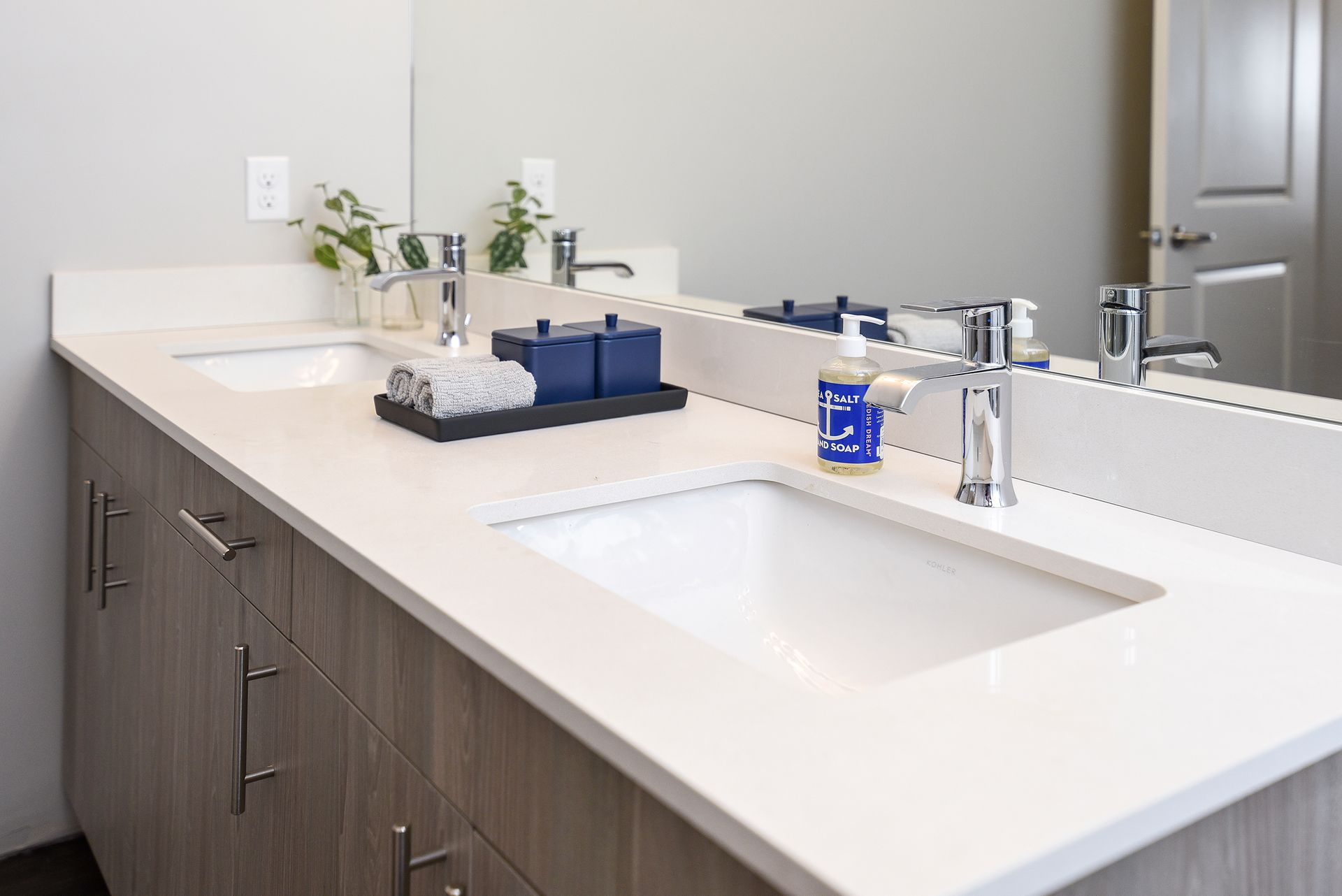 Bathroom with two sinks, a large mirror, and a light-colored countertop.