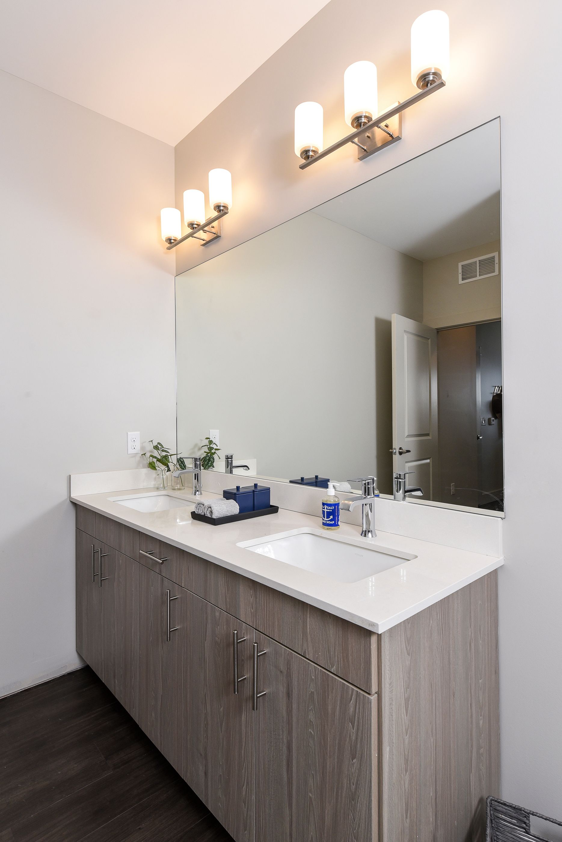 Bathroom with double vanity, large mirror, and three light fixtures.