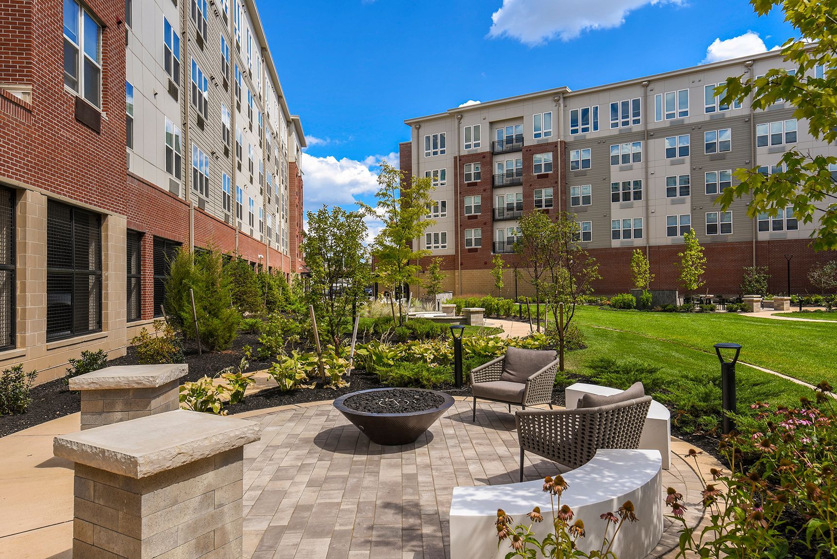Courtyard with seating, fire pit, and apartment buildings on a sunny day.